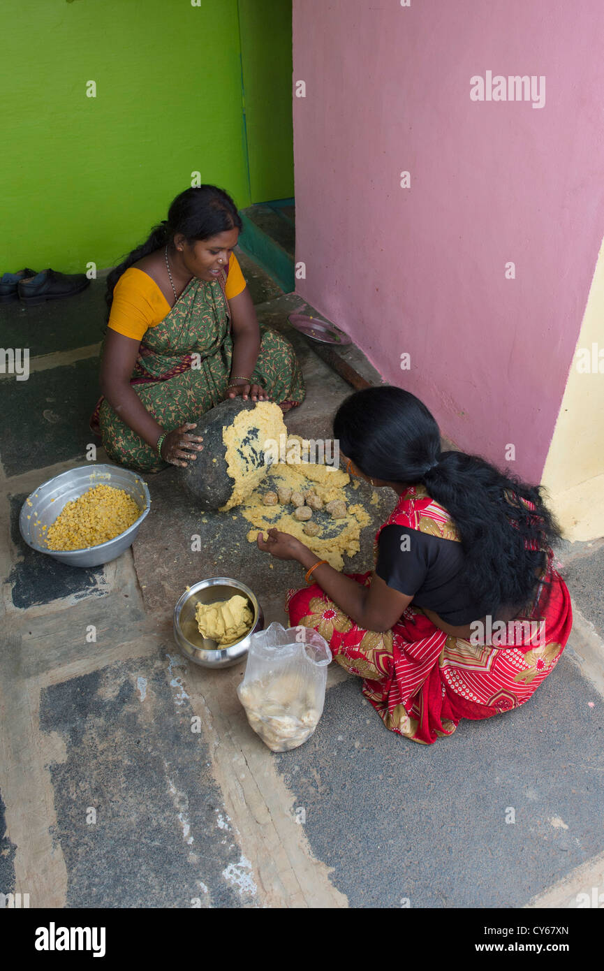 Les femmes indiennes le mélange de Jagré Dal mélange avec une meule en pierre pour faire des bonbons festival Dasara dans un village de l'Inde rurale. L'Inde Banque D'Images