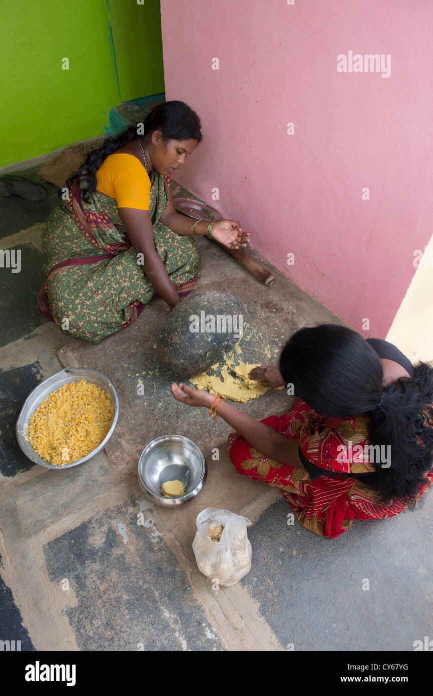 Les femmes indiennes le mélange de Jagré Dal mélange avec une meule en pierre pour faire des bonbons festival Dasara dans un village de l'Inde rurale. L'Inde Banque D'Images