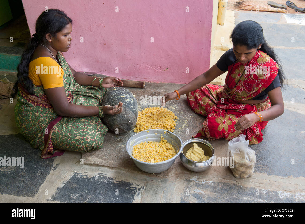 Les femmes indiennes le mélange de Jagré Dal mélange avec une meule en pierre pour faire des bonbons festival Dasara dans un village de l'Inde rurale. L'Inde Banque D'Images