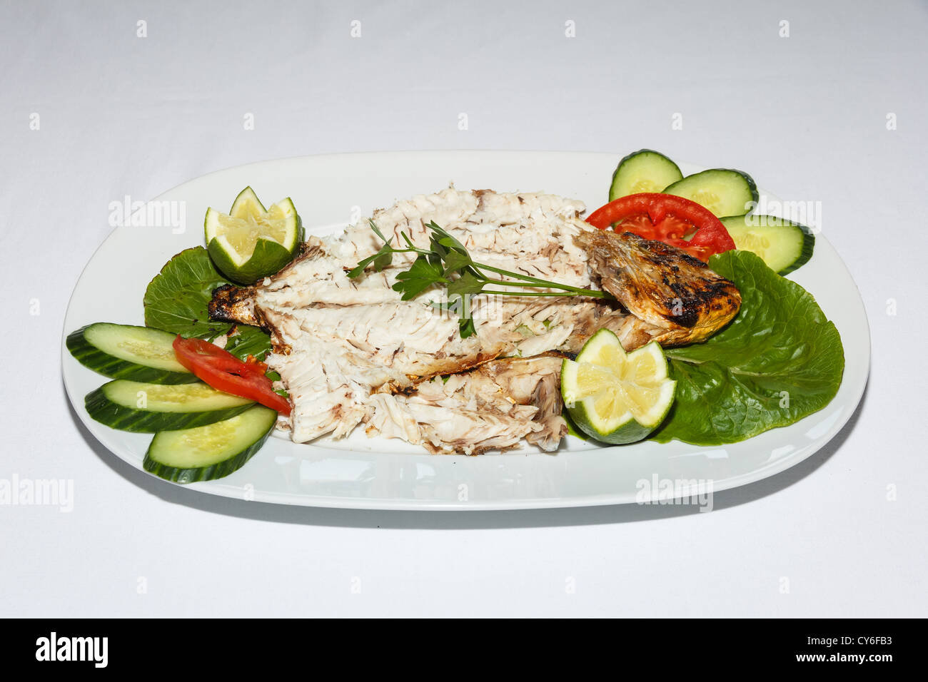 Le poisson cuit avec des légumes et des tranches de concombres dans une assiette Banque D'Images