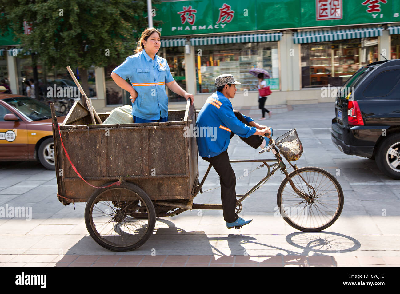 Une femme chinoise promenades dans l'arrière d'un tricycle corbeille en été à Pékin, Chine Banque D'Images