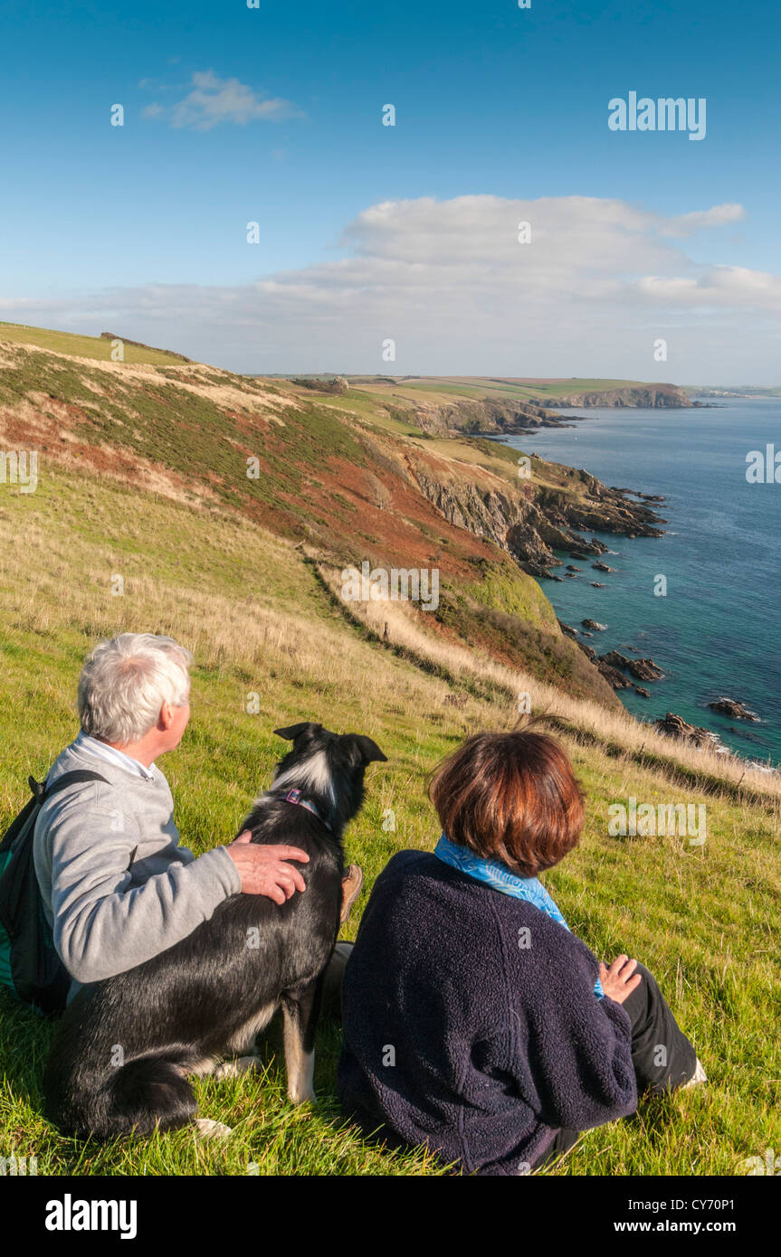 Un couple et leur chien profitant de la vue sur le sentier côtier du sud du Devon à l'est de Plymouth, en soirée d'été ensoleillée tard. ROYAUME-UNI Banque D'Images