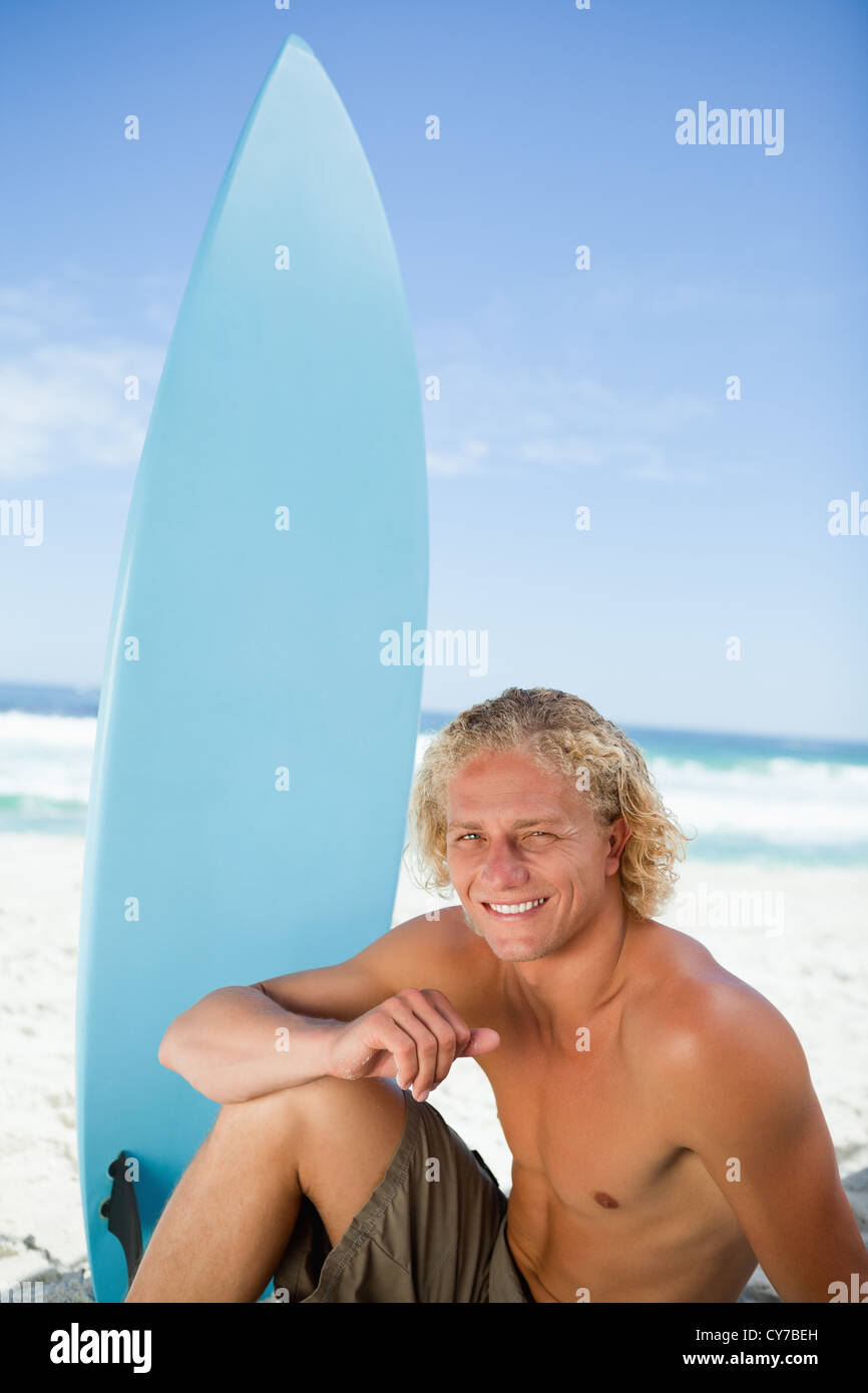 Couple assis sur la plage avec son bras sur sa jambe Banque D'Images