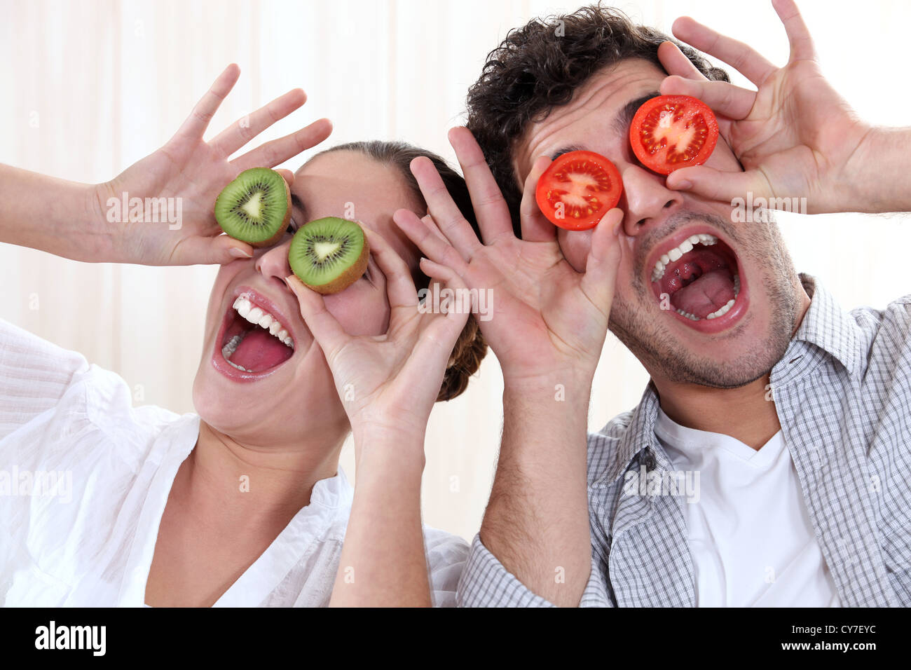 Couvrant ses yeux avec quelques tranches de tomate et kiwi Banque D'Images