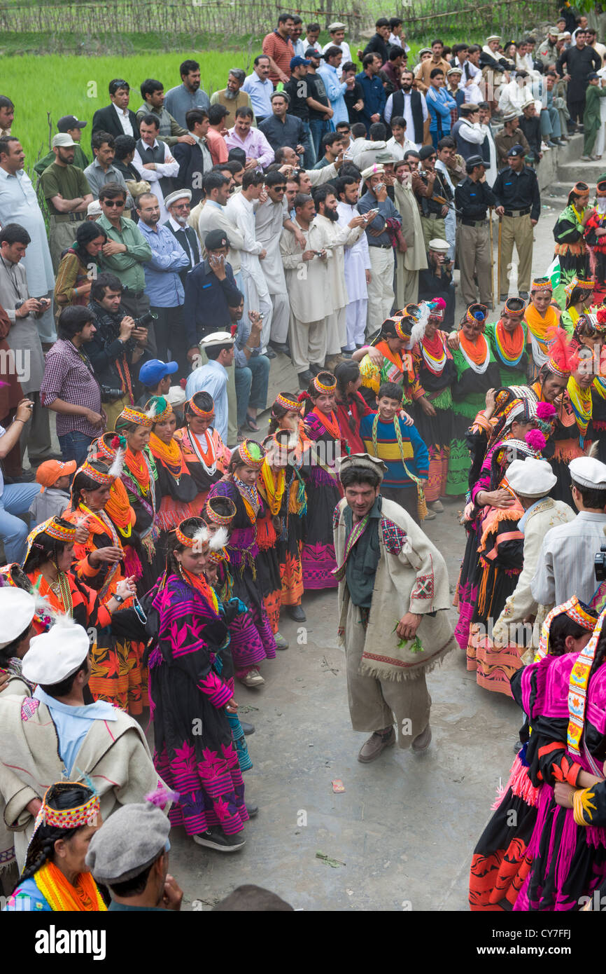Kalash l'homme et de la femme à danser à l'Anish Brun Village Charso (danse), surveillées par des foules d'hommes musulmans, Kalash Joshi (Fête du Printemps), la vallée de Bumburet, Chitral, Khyber-Pakhtunkhwa, Pakistan Banque D'Images