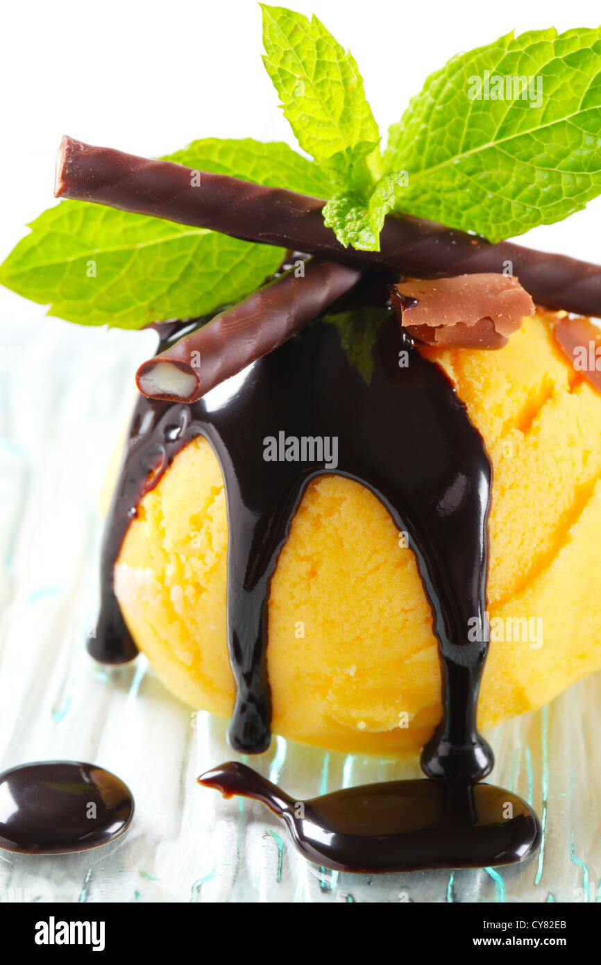 Boule de glace jaune garni de sauce au chocolat et menthe stick Banque D'Images