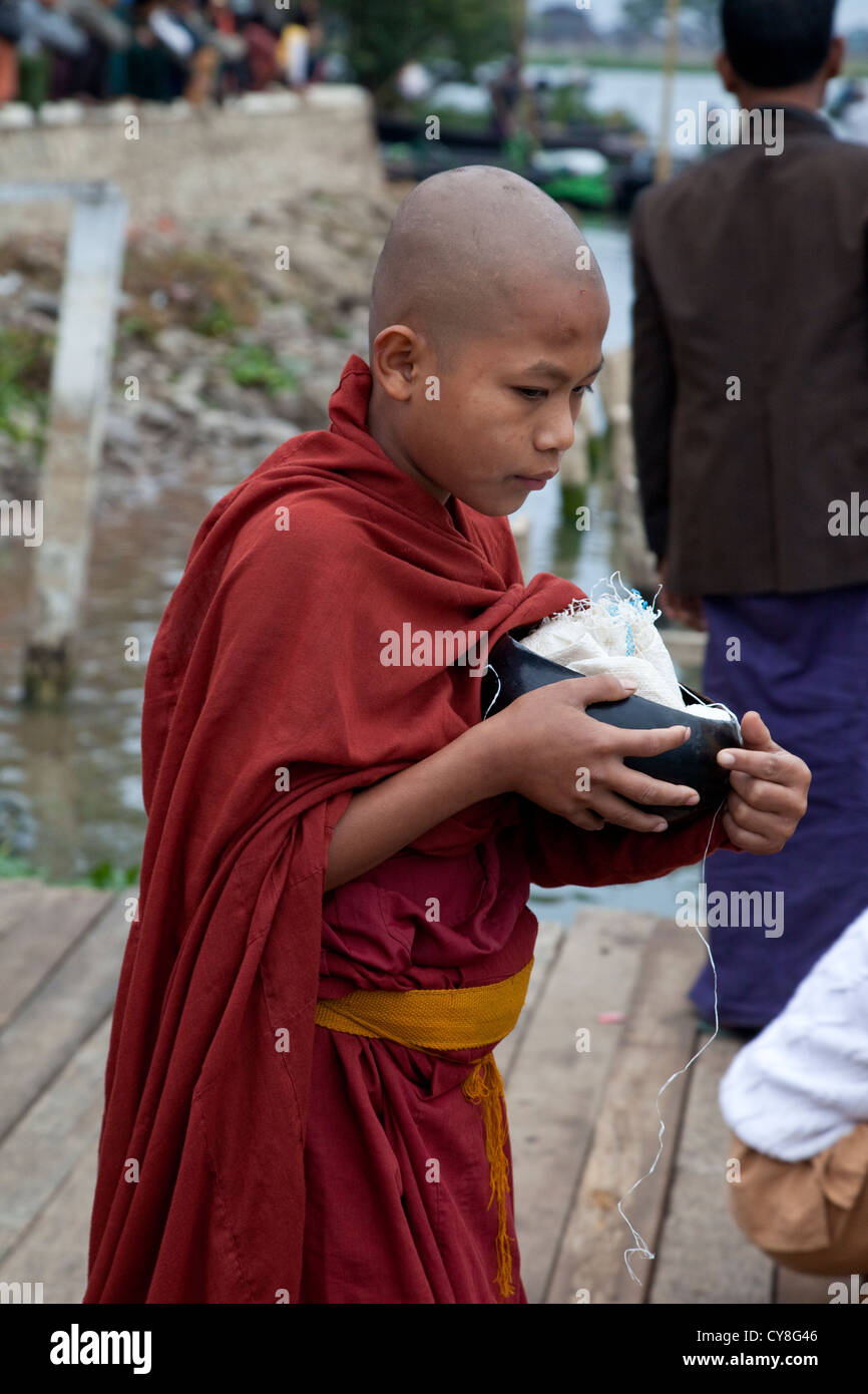 Le Myanmar, Birmanie. Jeune Moine transportant des Birmans Mendicité, Alodaw Pauk Pagode, Nampan Village, lac Inle, l'État Shan. Banque D'Images
