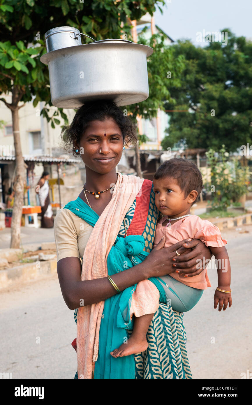 Pauvre basse caste indienne avec bébé portant un pot de riz sur la tête. L'Andhra Pradesh, Inde Banque D'Images