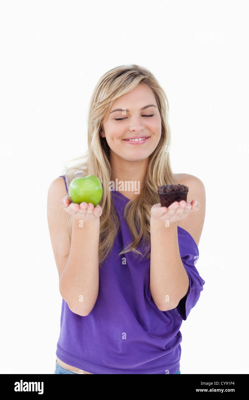 Smiling blond woman holding un fruit et un muffin Banque D'Images