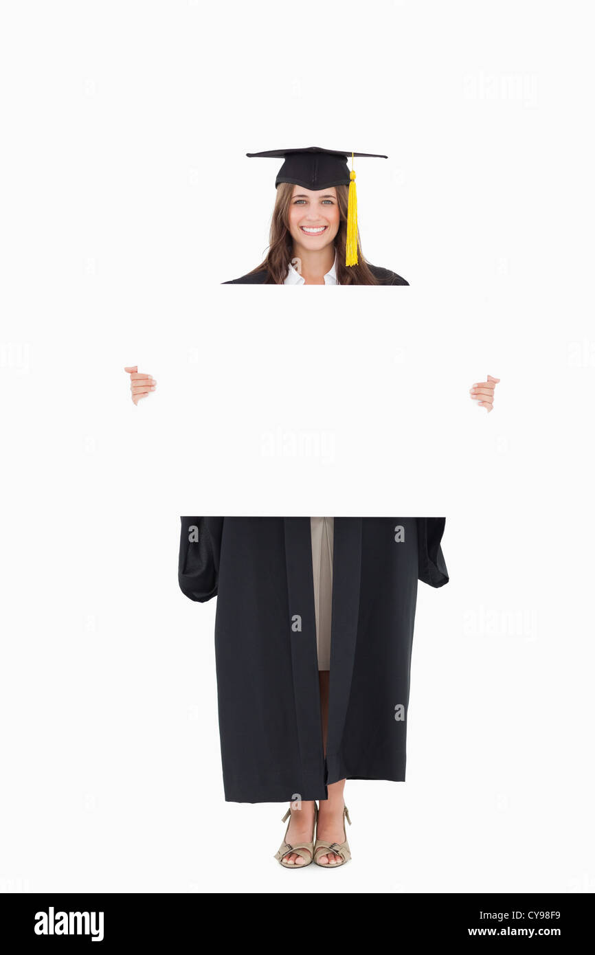 Longueur totale d'une femme tenant une feuille blanche devant elle comme elle sourit Banque D'Images