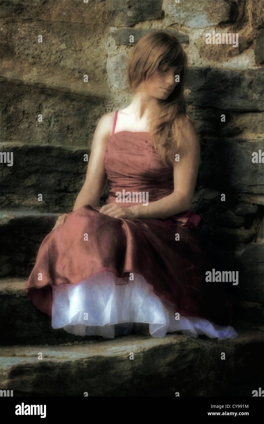 Une femme dans une robe rouge assis sur les marches de pierre Photo Stock Alamy