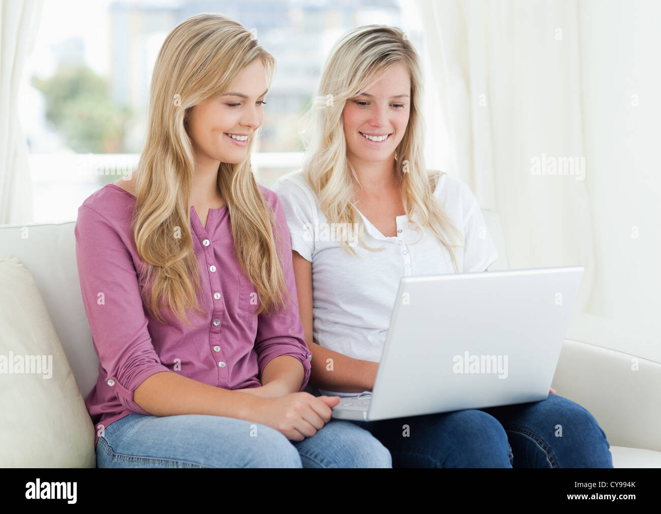 Une fille et de son ami à la recherche tandis que d'un ordinateur portable sur le canapé Banque D'Images