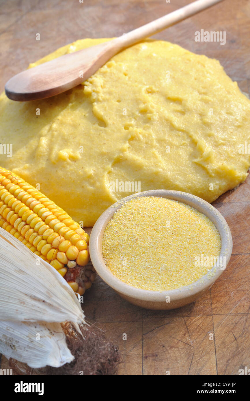 Bol de farine de maïs sur planche de bois avec de la polenta et épi de blé Banque D'Images
