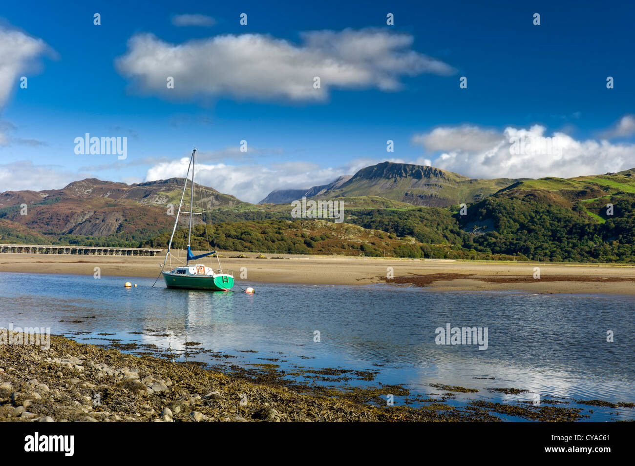 Un yacht à coque verte est ancrée dans l'estuaire de mawddach, marée basse, cadair idris montagnes en arrière-plan, paisible, sun Banque D'Images