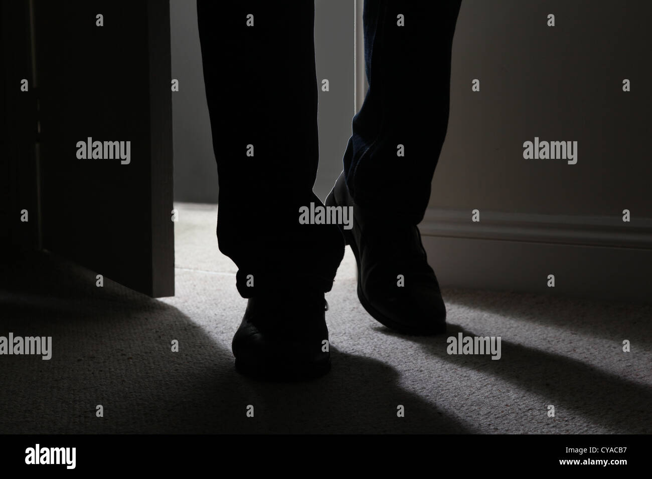 Homme portant des chaussures noires entre dans une pièce sombre, de rétroéclairage. Close up Banque D'Images