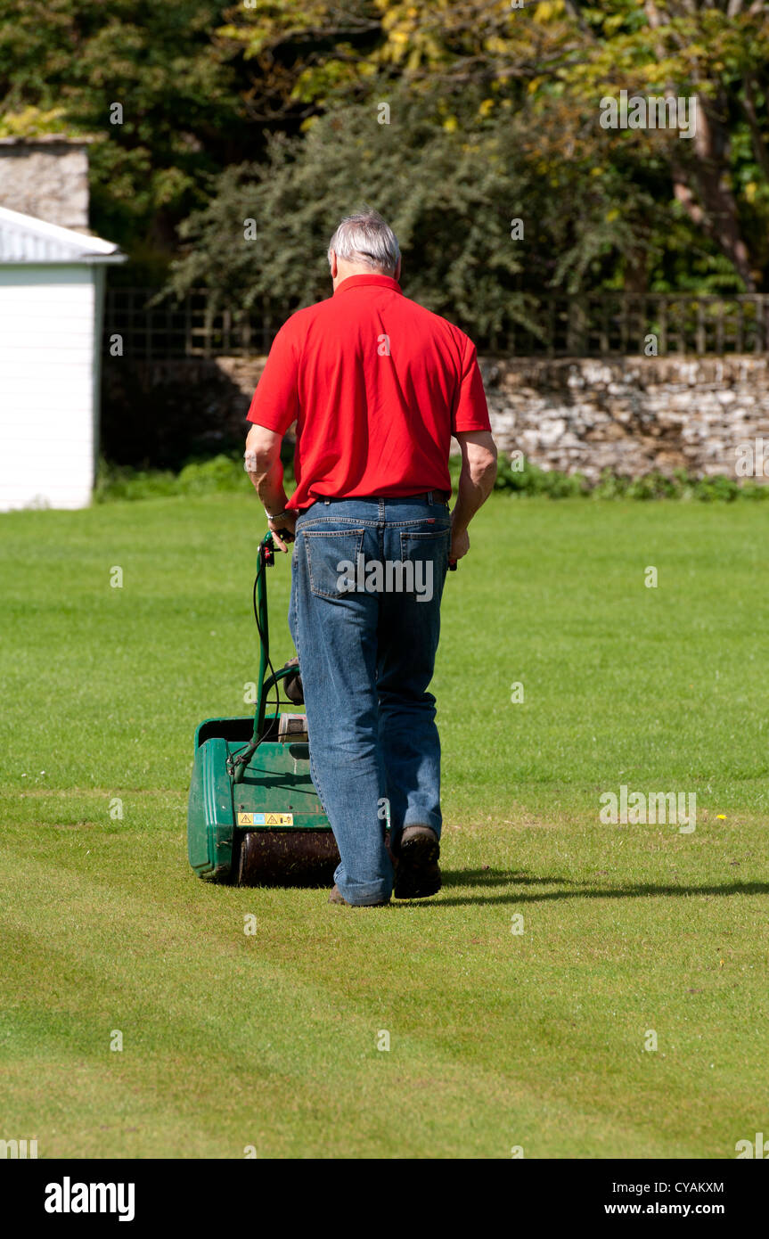 Man mowing terrain de cricket du village Banque D'Images