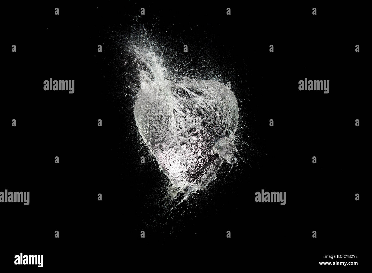 Ballon d'eau en forme de coeur de rupture sur un fond noir Banque D'Images