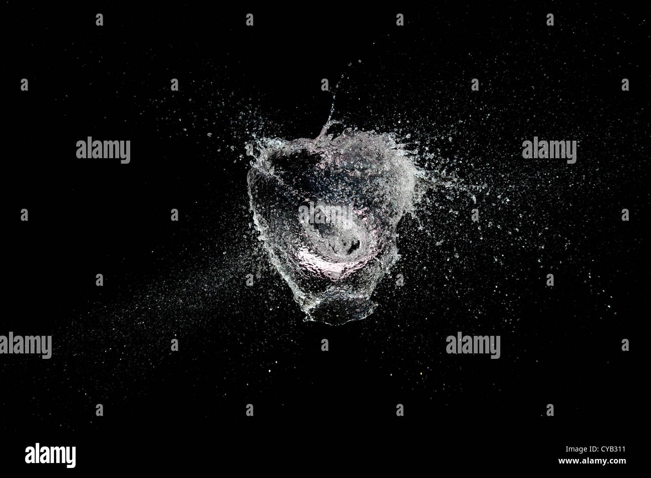 Ballon d'eau en forme de coeur de rupture sur un fond noir Banque D'Images