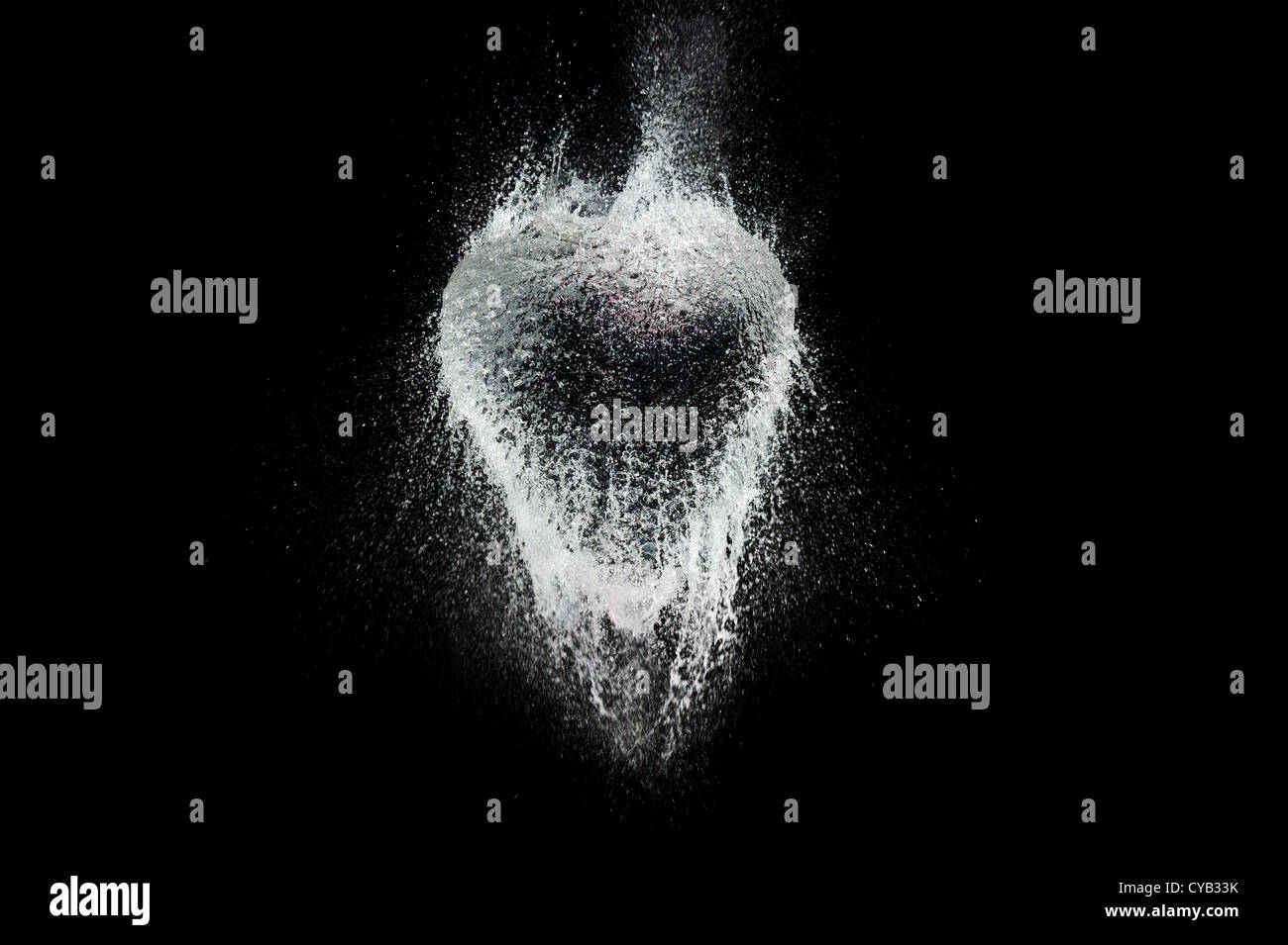 Ballon d'eau en forme de coeur de rupture sur un fond noir Banque D'Images