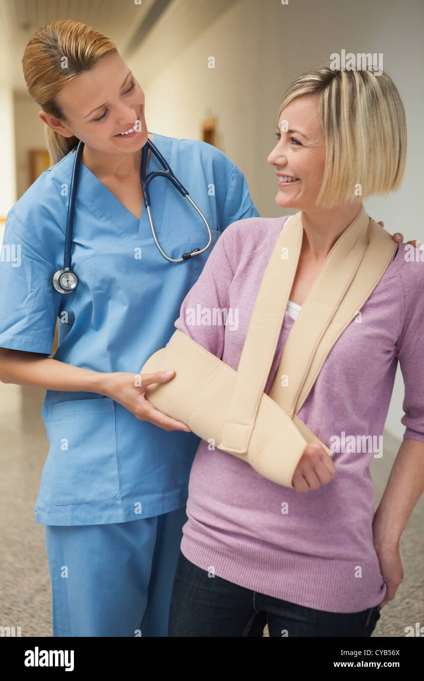 Nurse smiling patient avec bras en écharpe Banque D'Images