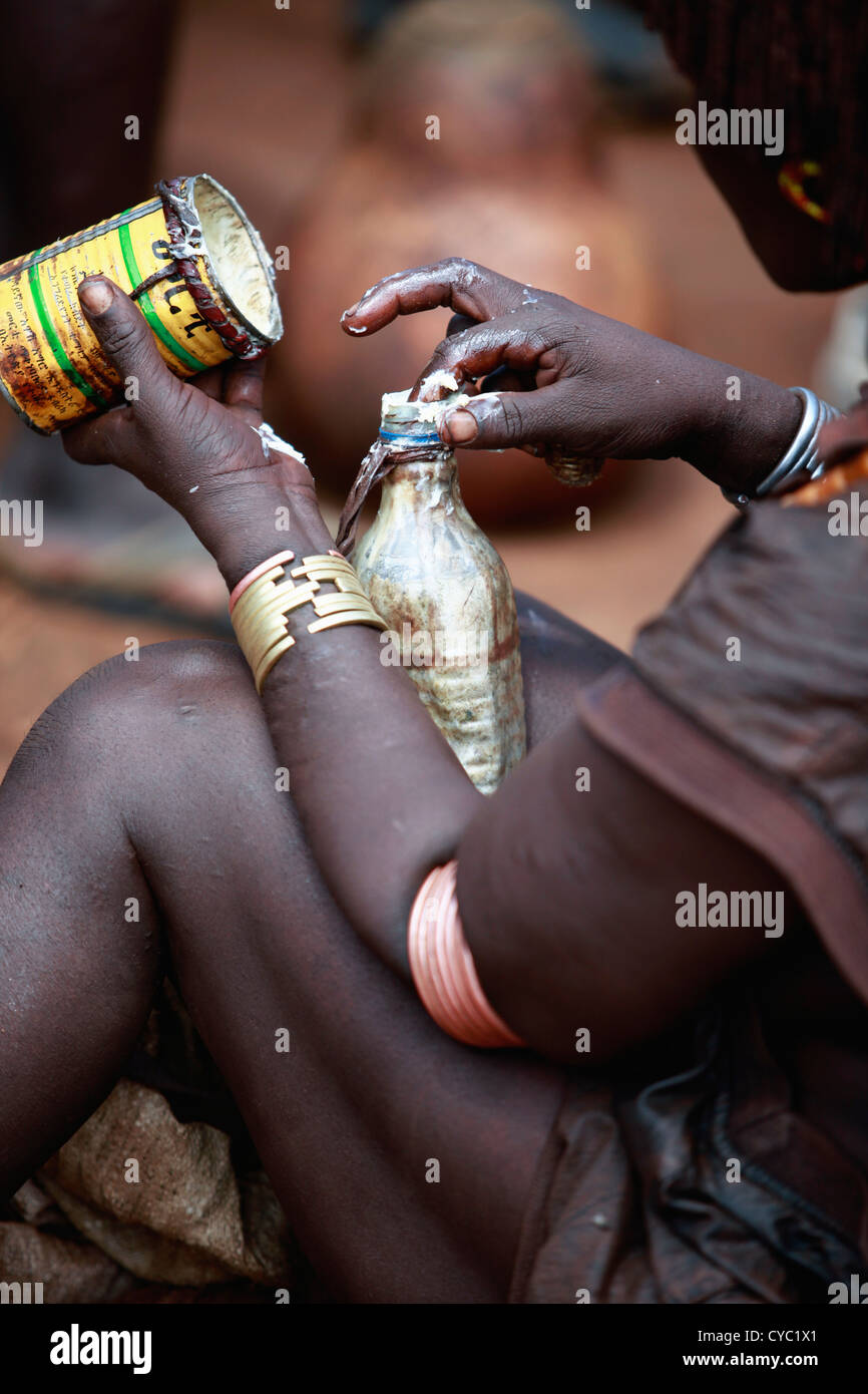 Femme Hamar Tribal mettre le beurre dans une bouteille en plastique. Banque D'Images