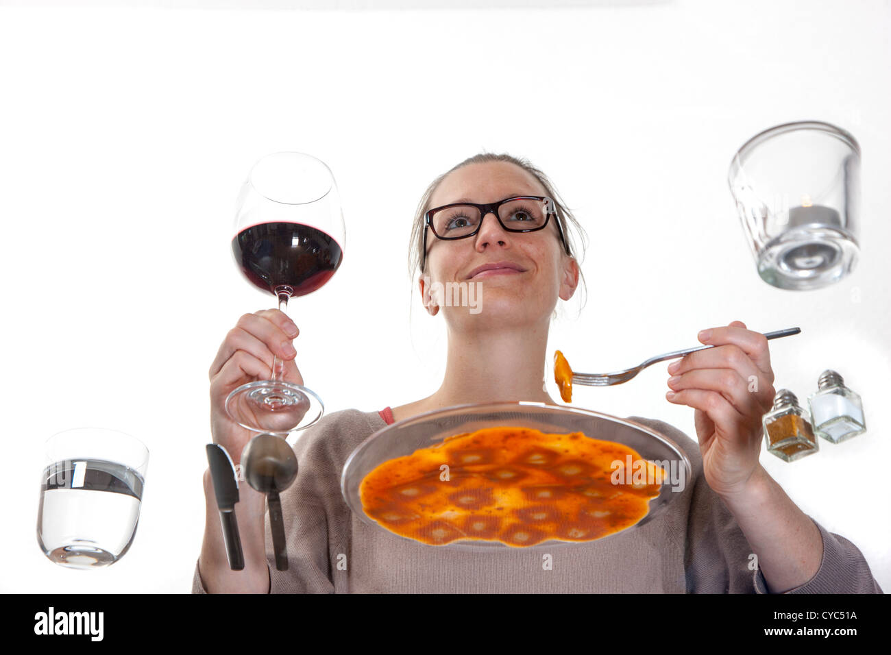 Jeune femme est assis à une table en verre. Manger des pâtes, ravioli avec une sauce tomate, eau minérale, verre de vin rouge. Banque D'Images