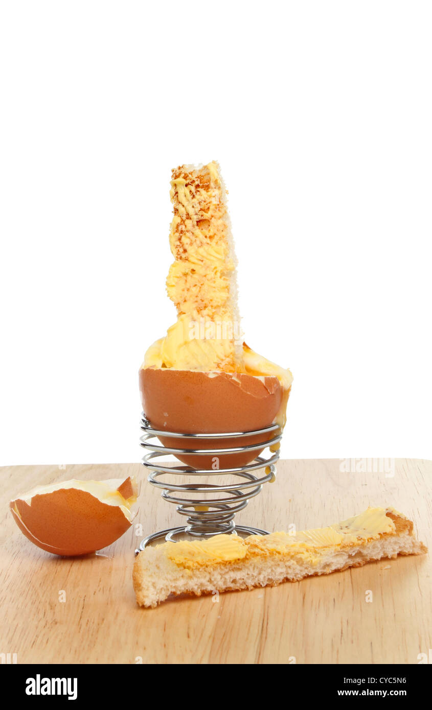 Oeufs à la coque avec du pain grillé dans un fil soldat egg cup sur une planche en bois Banque D'Images
