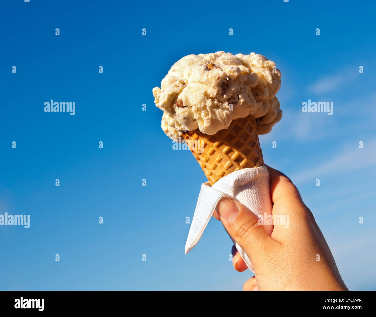 Icecream cône maintenu jusqu'à la hot summer sky Banque D'Images