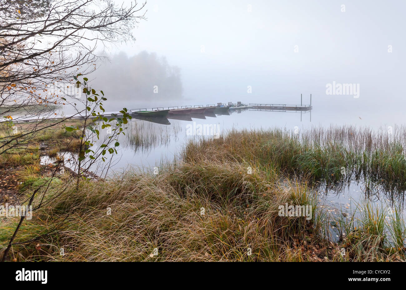 Petit bâtiment avec des bateaux sur le lac dans le froid matin brumeux encore Banque D'Images