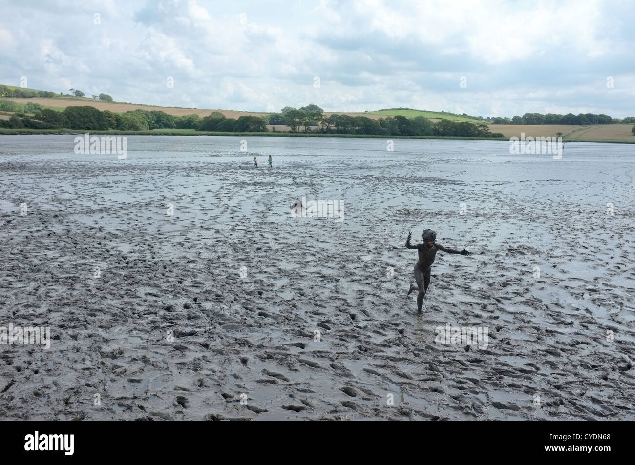 Enfants jouant dans la boue dans les eaux à marée de la rivière Lynher en Cornouailles. Banque D'Images