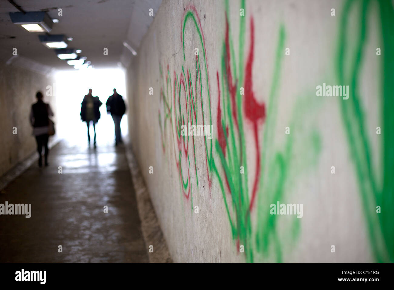 Graffiti sur le mur d'un passage souterrain. Une femme est suivi par deux hommes Banque D'Images