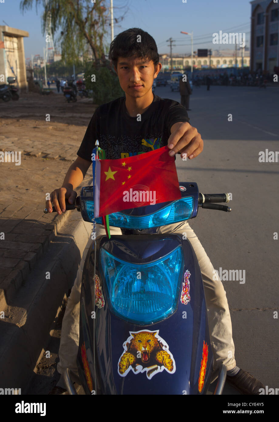 Uyghur Garçon montrant un drapeau chinois, Kashgar, la région autonome ouïghoure du Xinjiang, Chine Banque D'Images