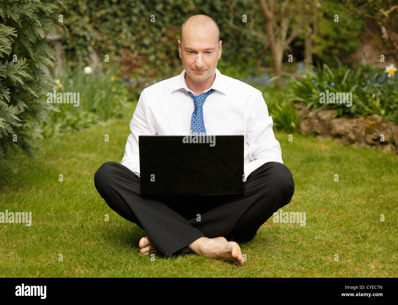 Homme d'affaires réussi en chemise blanche et cravate vrksasana de travail d'un ordinateur portable dans un jardin Banque D'Images