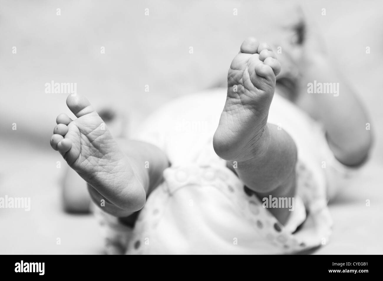 Heureux mignon bébé nouveau-né les pieds avec les orteils et les rides. Bébé portant sur le dos. Banque D'Images