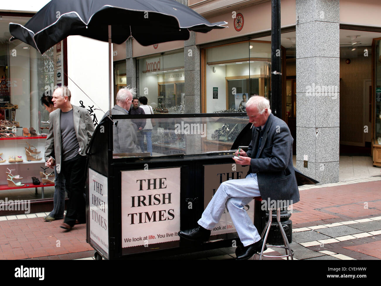 Un vieux vendeur de journaux assis dans Grafton Street, Dublin, Irlande Banque D'Images