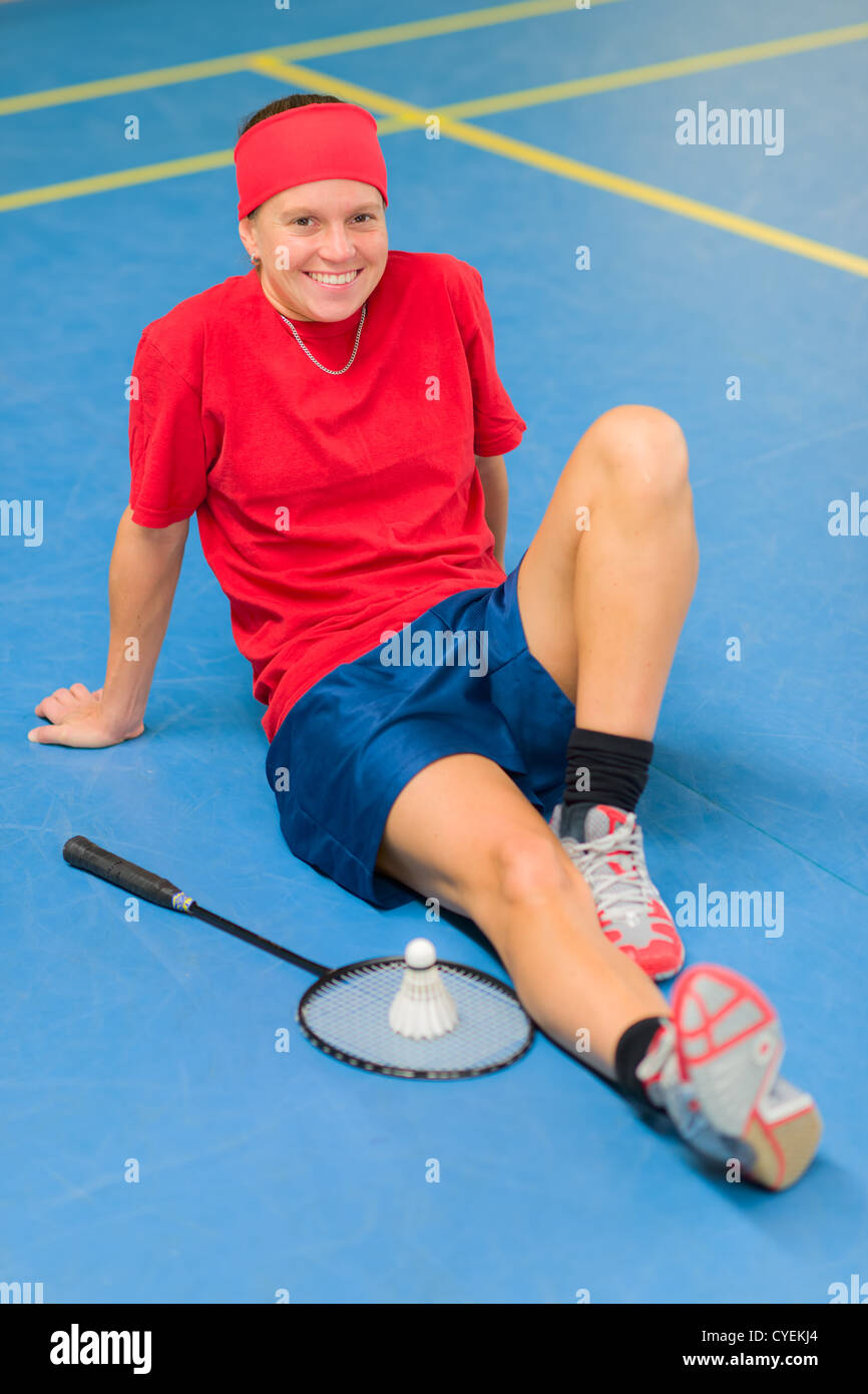 Badminton joueur assis sur la cour, à côté de la navette et de raquette. Banque D'Images