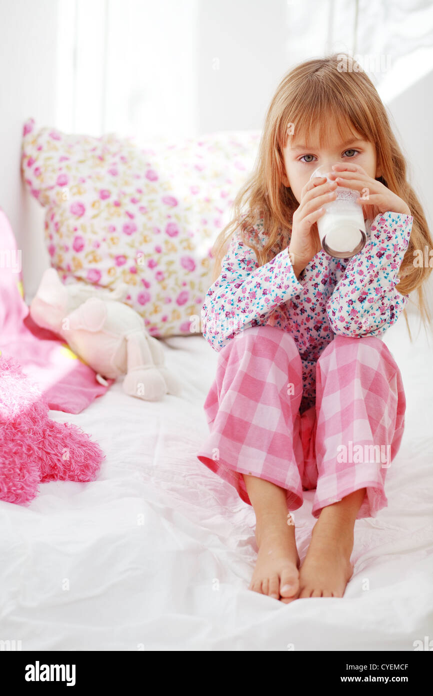 Home portrait de l'enfant de boire du lait au lit Banque D'Images