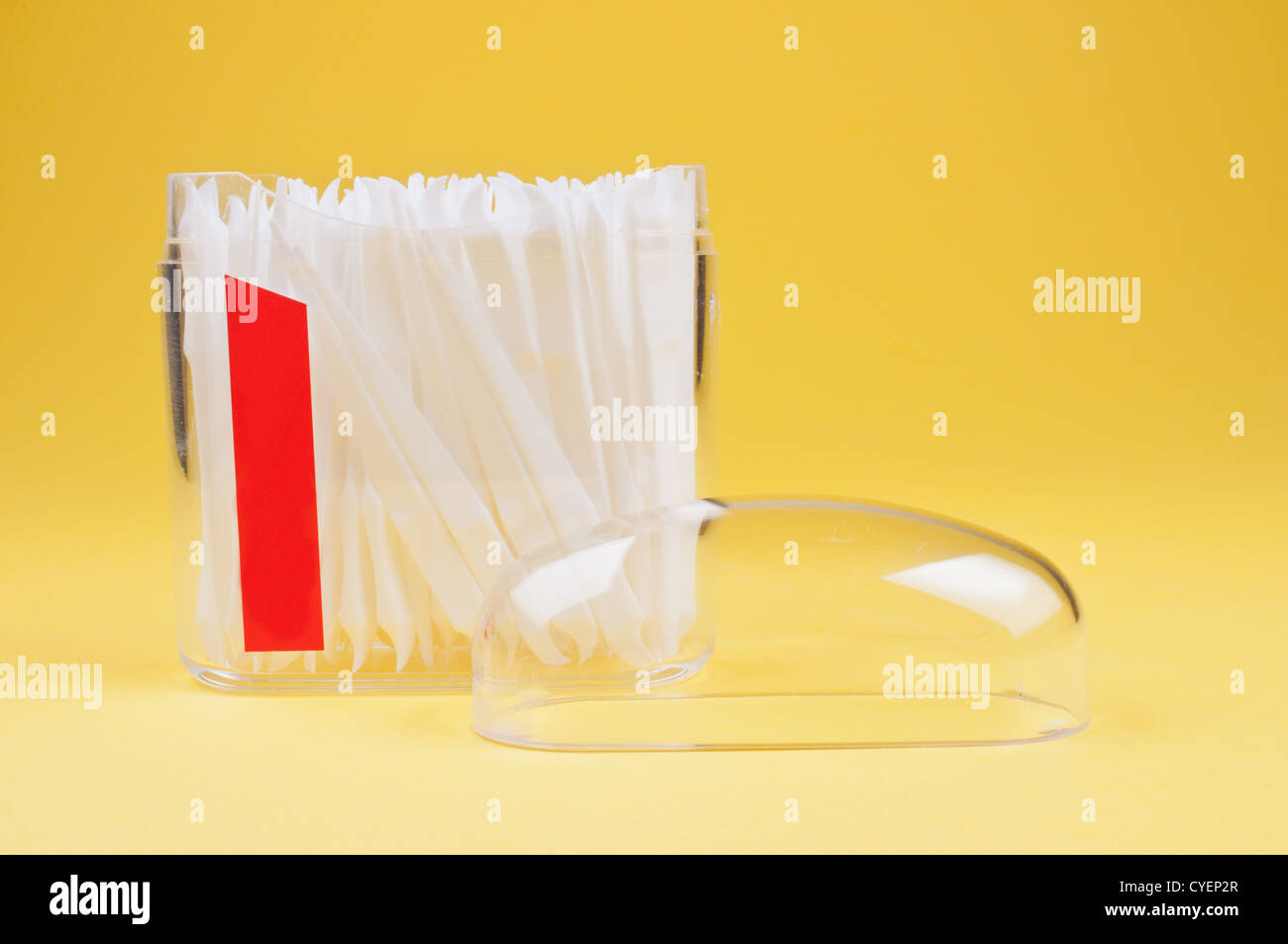 Cure-dents dans un contenant de plastique clair sur fond jaune Banque D'Images