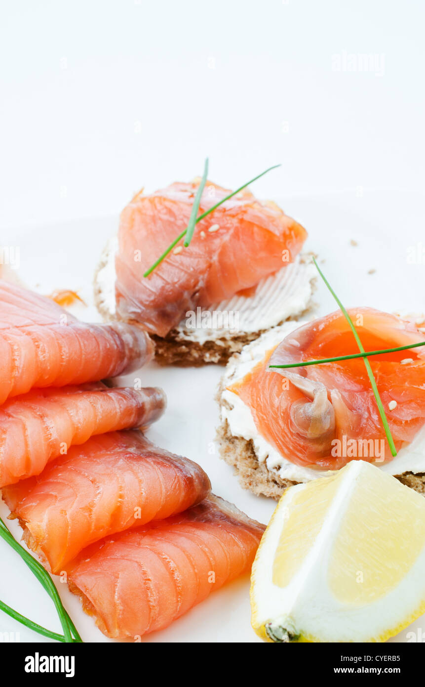 Pièces de saumon fumé avec des canapés et des citrons et ciboulette Banque D'Images