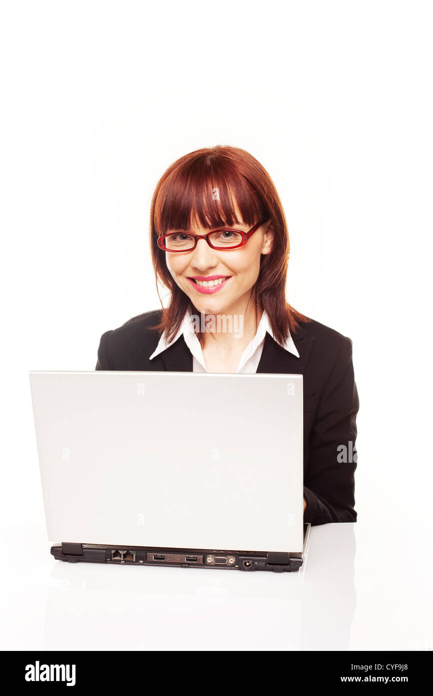 Smiling redhead businesswoman efficace secrétaire ou assis derrière son ordinateur portable travailler Banque D'Images