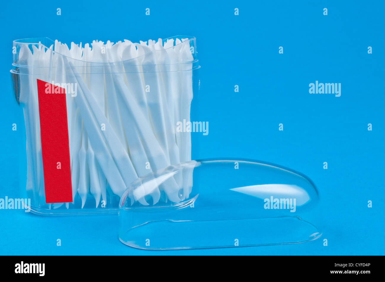 Cure-dents dans un contenant de plastique clair sur fond bleu Banque D'Images