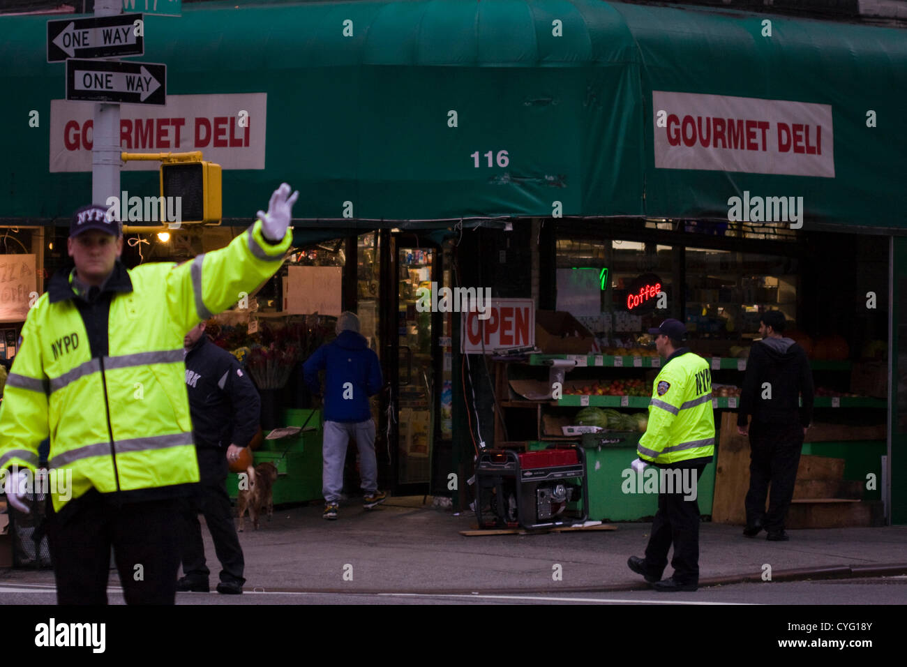 New York USA. 1er novembre 2012. Les agents de police de la police de porter des vestes réfléchissantes trafic direct au crépuscule sur la 17ème Rue et 7ème Avenue, dans le quartier de Chelsea, New York City. Une sur le coin Gourmet Deli est ouvert au public seulement parce qu'il est de l'énergie électrique à partir d'un générateur portable rouge sur le trottoir. Parties de la ville restent dark à cause d'une coupure à Manhattan en dessous de 29e st contre les effets de l'Ouragan Sandy qui a frappé la région le lundi 29 octobre. Banque D'Images