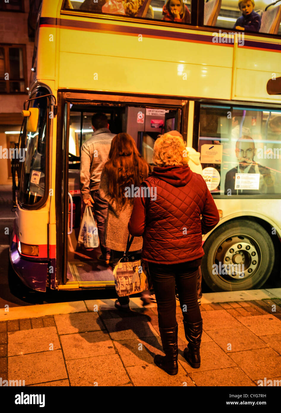Les personnes en attente d'un bus dans l'obscurité après le travail à Weymouth Banque D'Images