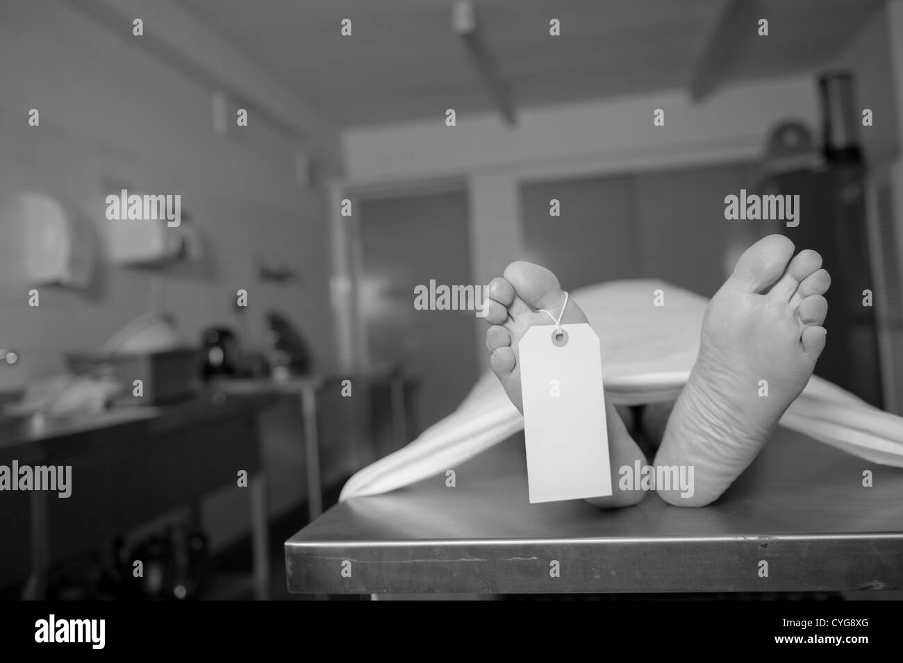 Corps Mort, allongé sur une table en métal dans une morgue. Il y a une balise vide fixée à l'un des pieds. Posée par un modèle - pas mort. Banque D'Images