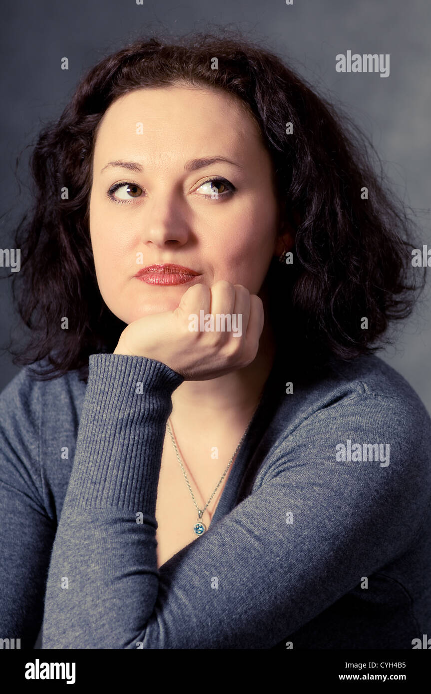 Portrait d'une femme pensive sur fond sombre Banque D'Images