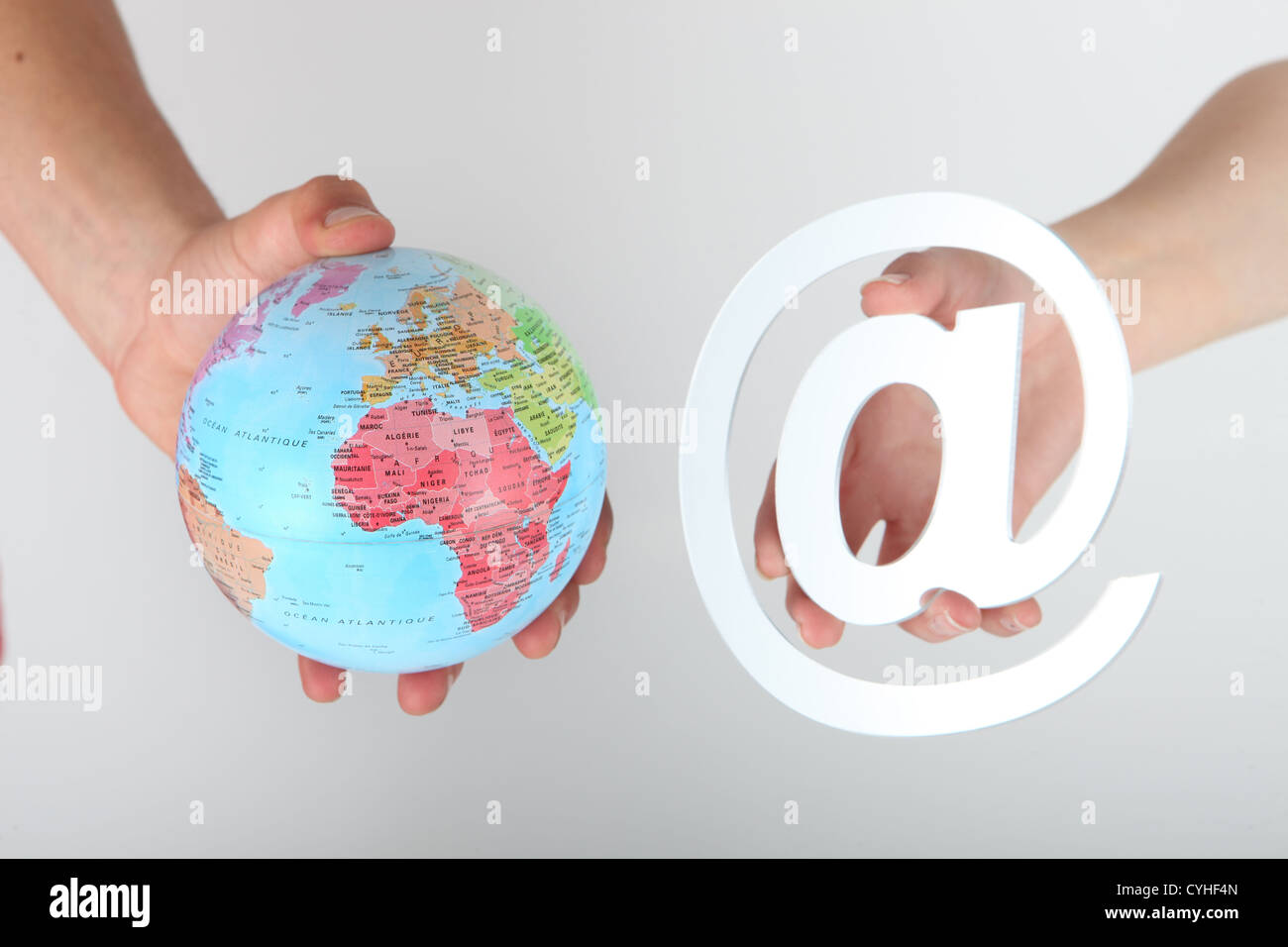 Les mains tenant un globe et un signe @ Banque D'Images