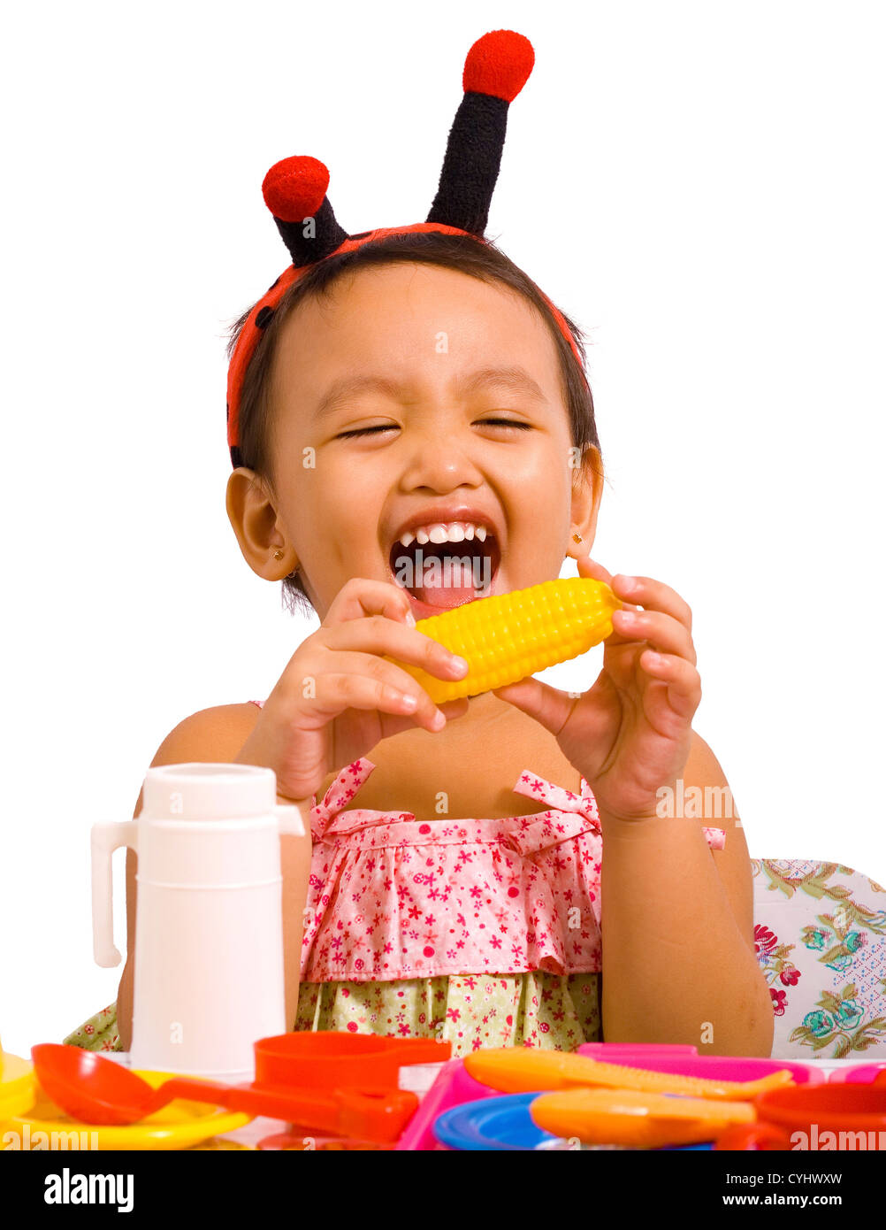 Girl Playing With Toy de l'alimentation et fait semblant de manger le maïs Banque D'Images