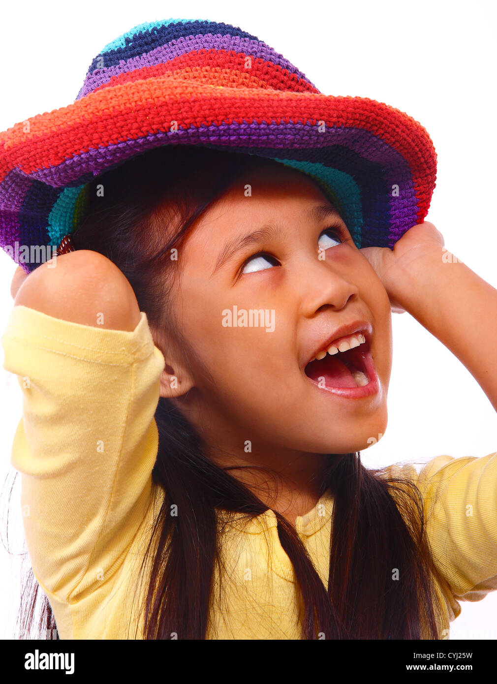 Souriant et heureux Girl Putting sur un Chapeau multicolore Banque D'Images