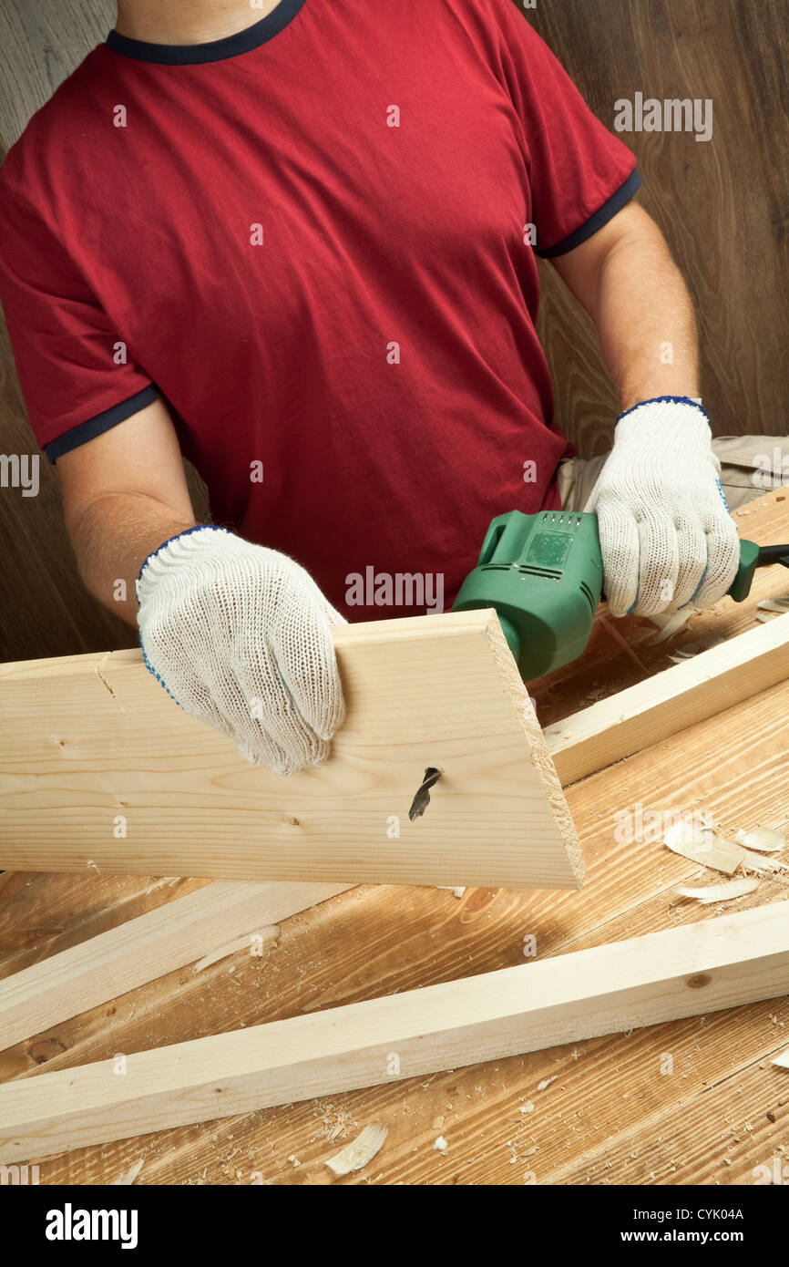 Atelier en bois avec la table d'outils. Les bras de l'homme planche de forage. Banque D'Images