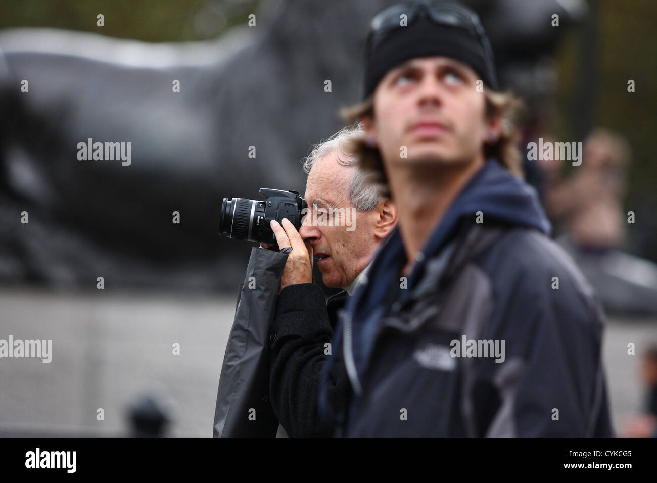 Un homme de prendre une photo à côté d'un homme qui est de la recherche. L'un des lions de Trafalgar Square à l'arrière-plan Banque D'Images
